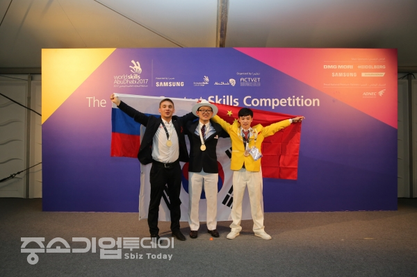 제2회 공조냉동기술 민간기능경진대회 우승자 최승우 군(가운데)이 2017년 UAE 아부다비에서 개최된 세계기능올림픽대회에서 우승을 차지한후 대회장에서 기념촬영을 갖고 있다.